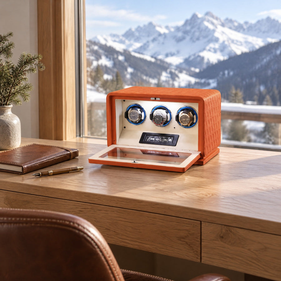 Remontoir 3 montres Méridien orange en cuir matelassé, porte ouverte, sur un bureau en chêne face à la montagne